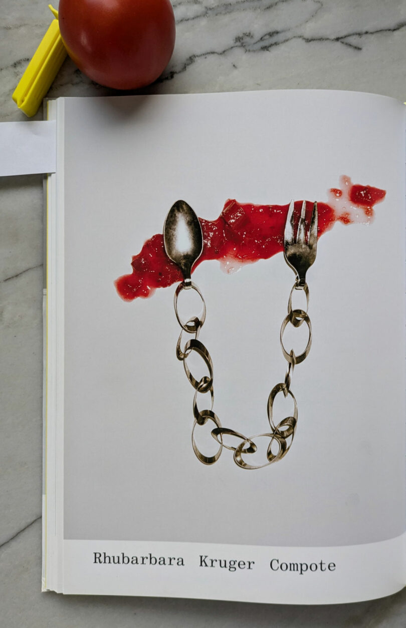 A book page displays a chain made of a spoon and fork on a red splatter, captioned "Rhubarbara Kruger Compote." Nearby, a tomato and highlighter rest—an arrangement reminiscent of Dana Harel’s conceptual style.