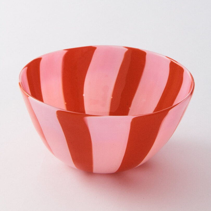 A round bowl with alternating vertical pink and red stripes on its exterior and interior, placed on a white surface—an eye-catching piece perfect for any 2025 Gift Guide.