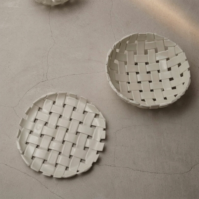 Two round, white ceramic baskets with a woven pattern are placed on a light, textured surface—perfect as stylish gifts for cooks.