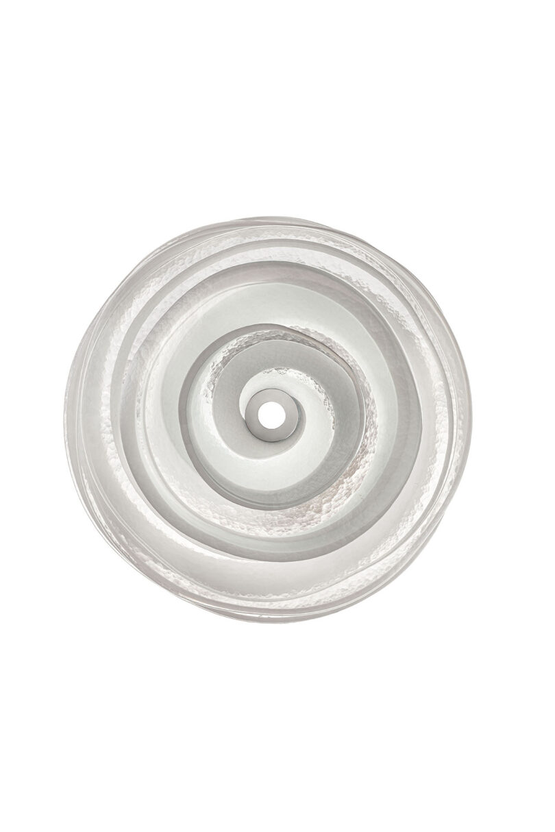 A round, translucent object with concentric swirl patterns and a hole in the center, viewed from above against a white background.