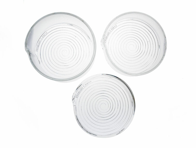 Three empty glass petri dishes with spiral patterns are arranged on a white background.