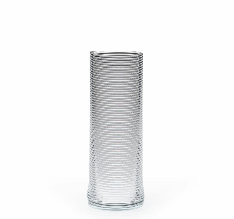 Clear glass vase with a tall, cylindrical shape and horizontal ribbed texture, photographed against a plain white background.