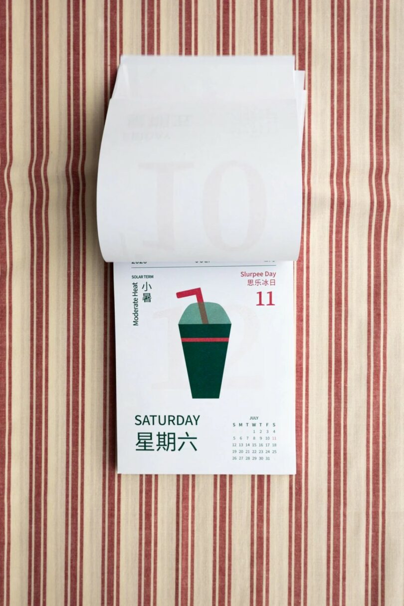 A calendar page for Saturday, July 11th, labeled "Slurpee Day," with an illustration of a green and red slush drink, placed on a red and beige striped fabric background