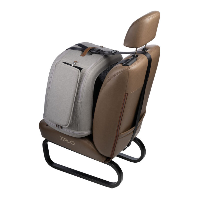 A gray travel bag is securely attached to the back of a brown car seat using a black strap