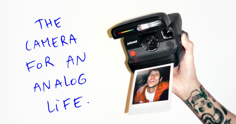 A tattooed hand holds a Polaroid camera printing a photo of a smiling person; handwritten text reads, "THE CAMERA FOR AN ANALOG LIFE.